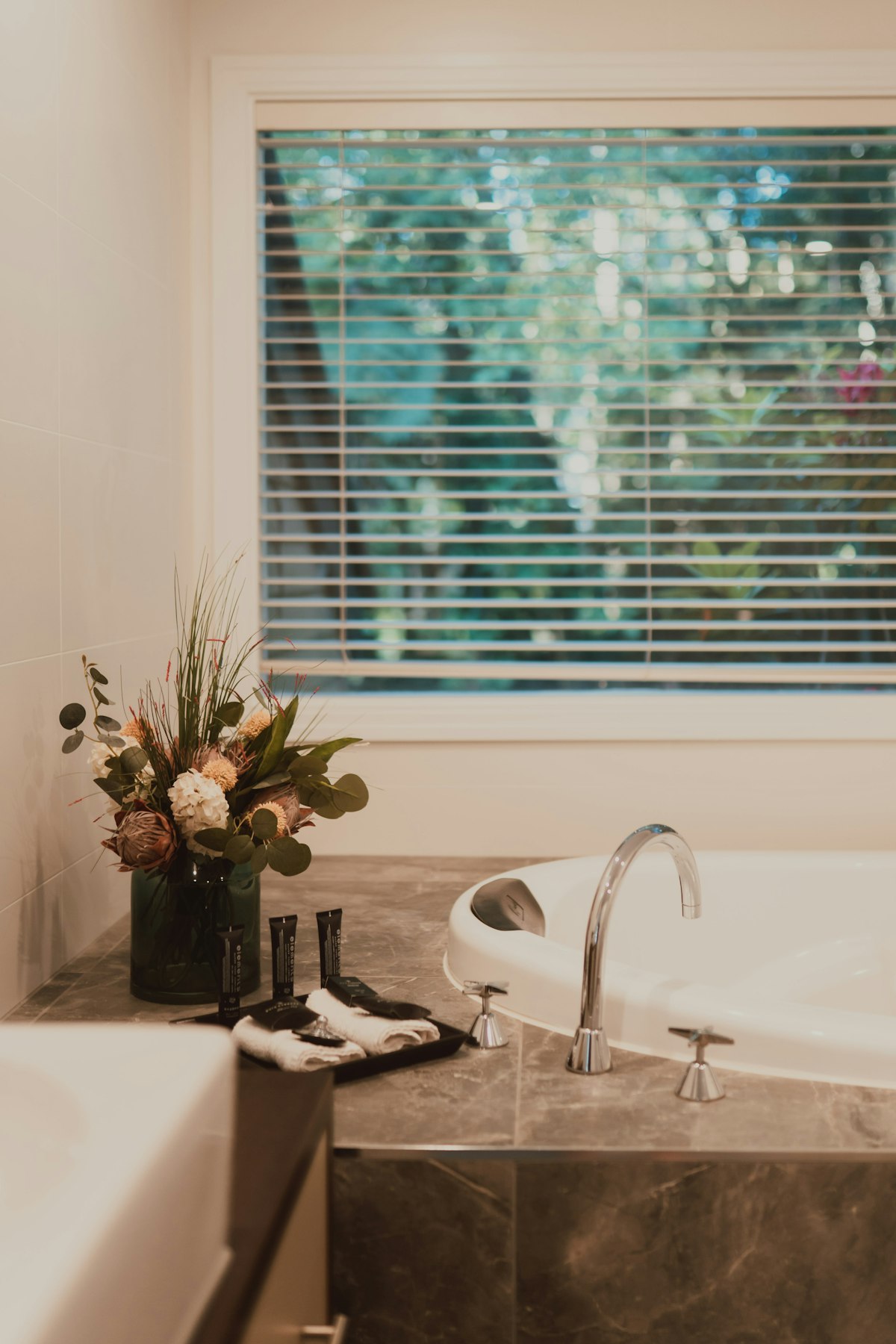 Bathroom with a bathtub, toiletries and a flower arrangement